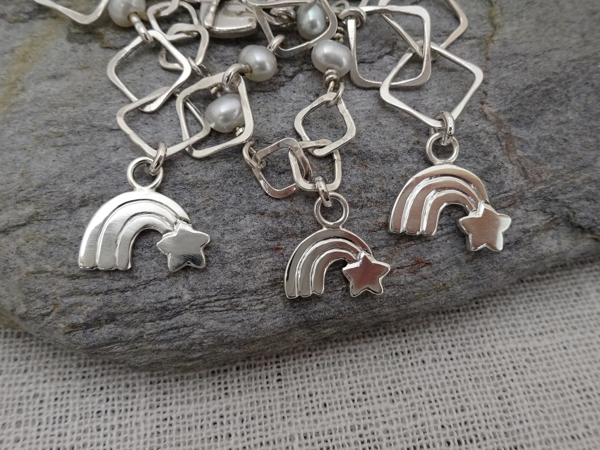Hangertjes van zilver van een regenboog met een sterretje.
