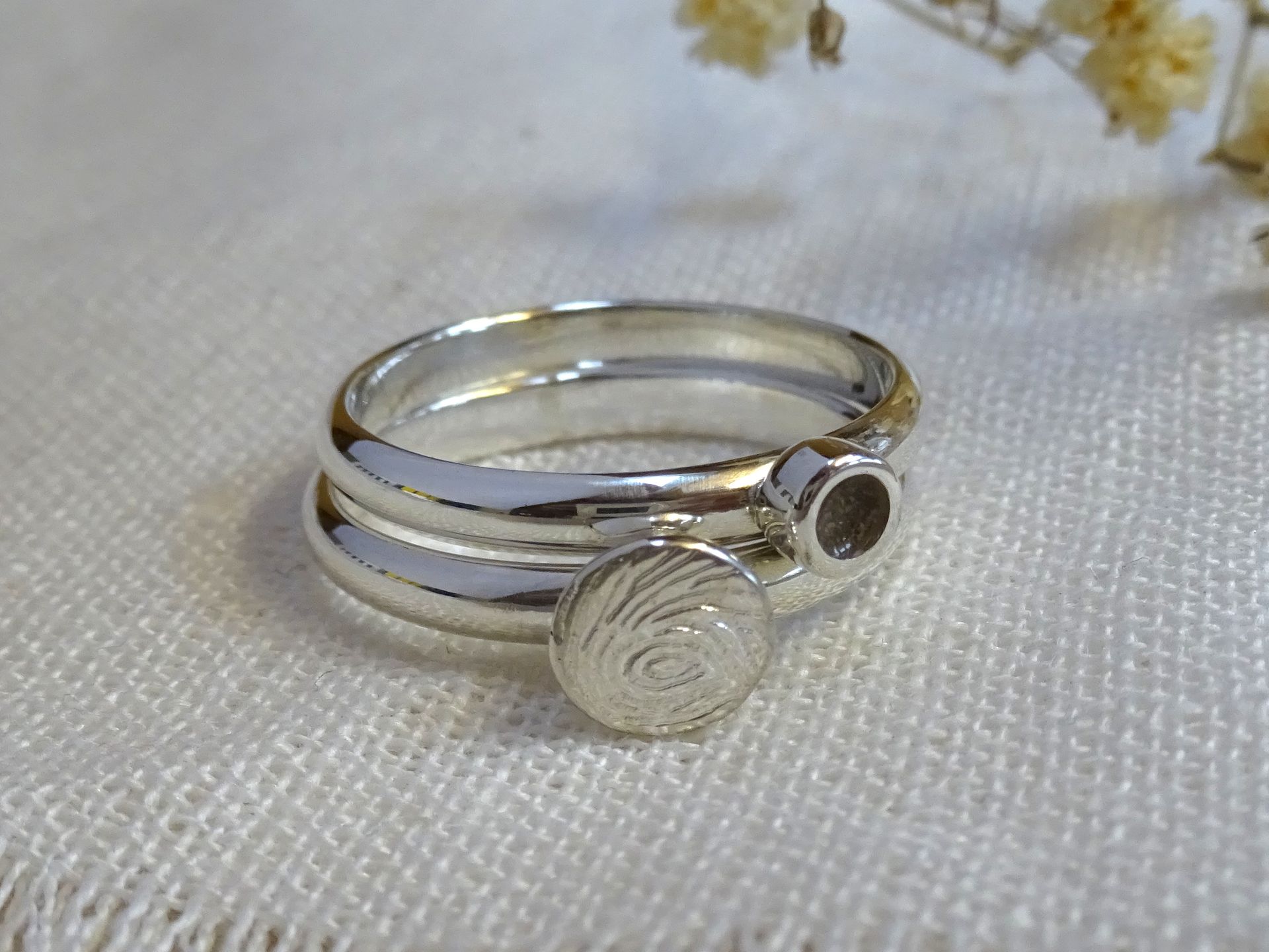 Zilveren herinnerringen met vingerafdruk en as van de overledene in hars gegoten.