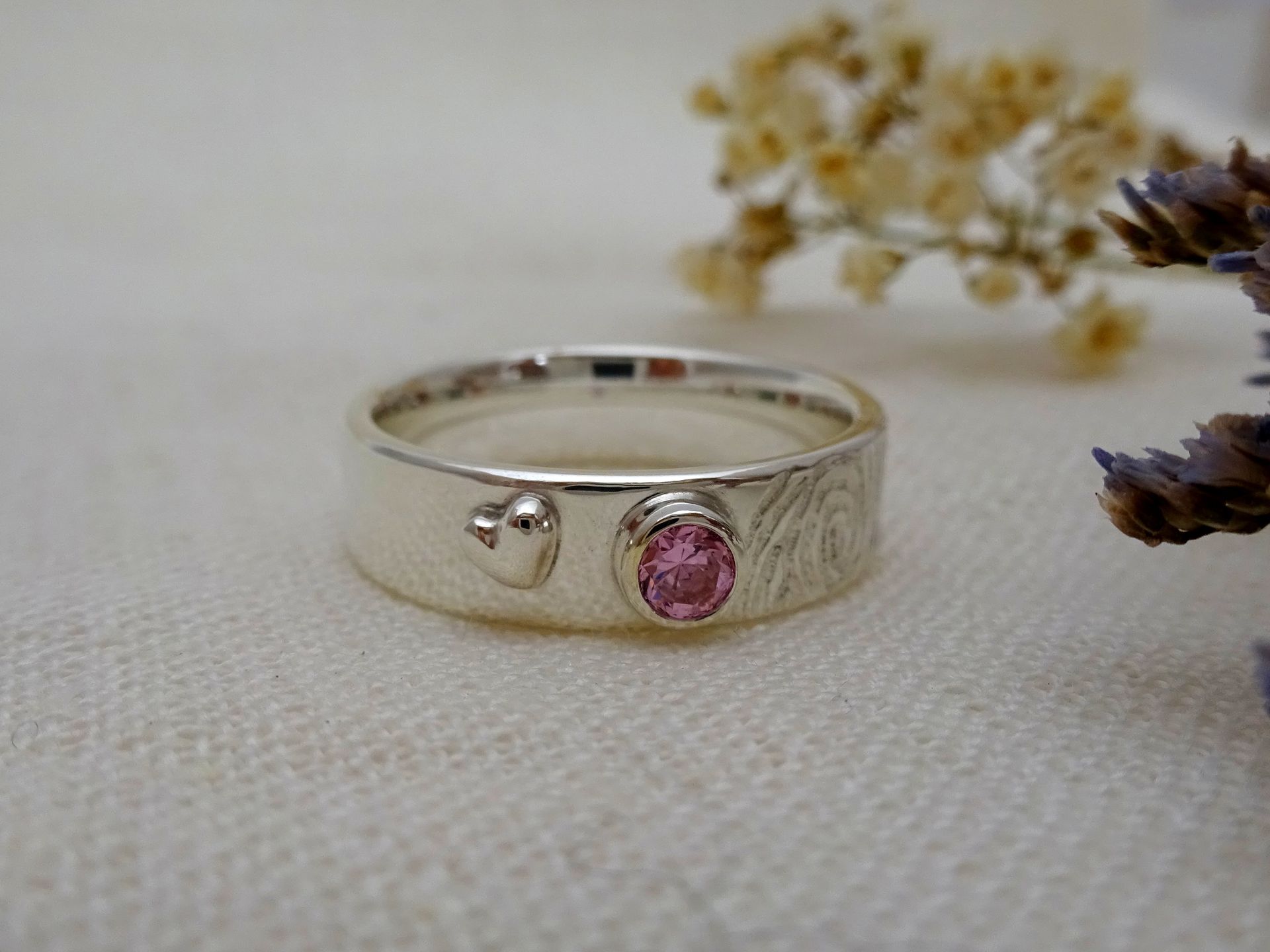 Herinnerring van zilver met vingerafdruk, as van de overledene, roze edelsteen en hartje.