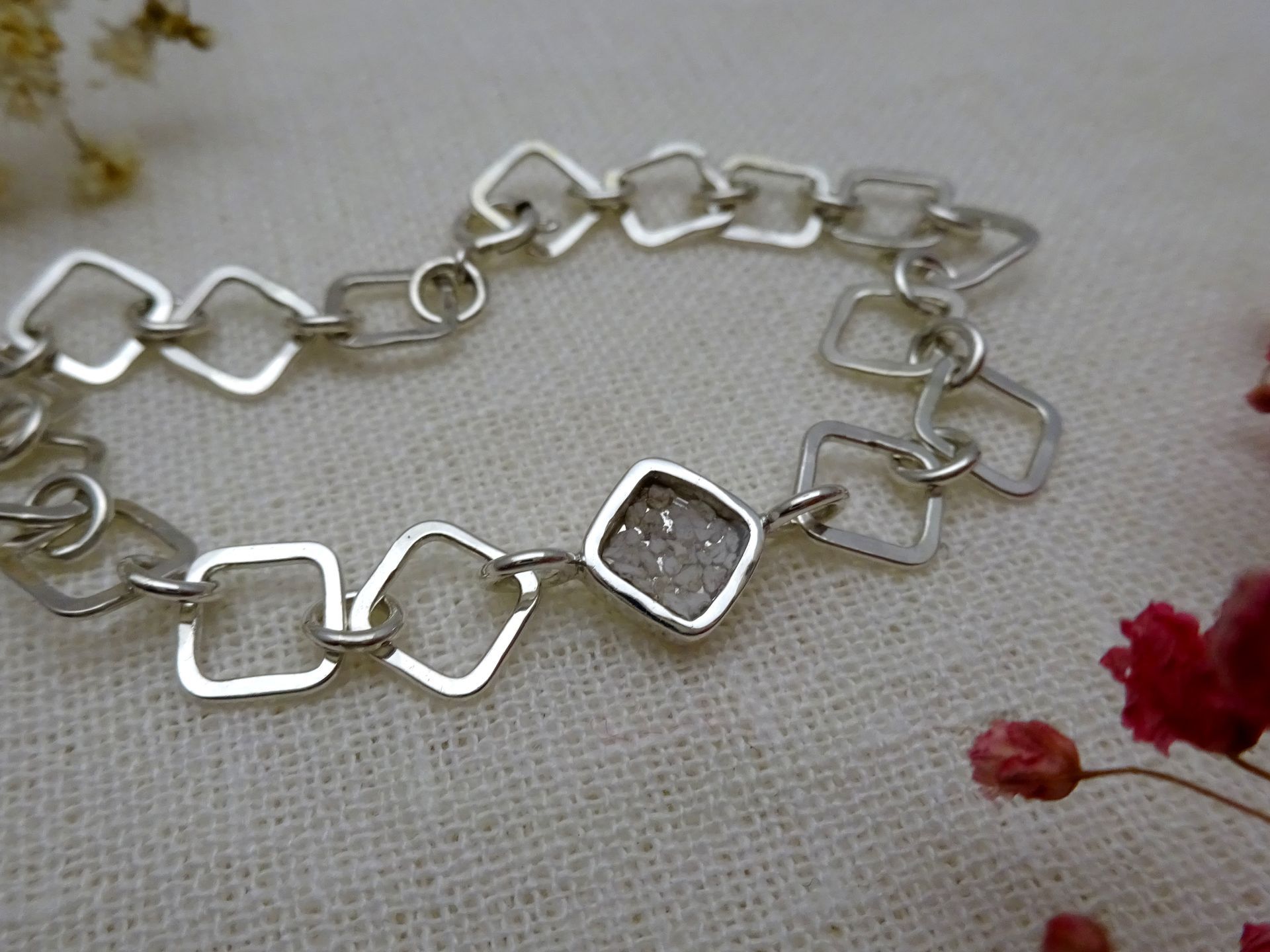 Schakelarmband van zilver met as van de overledene zichtbaar in hars gegoten.