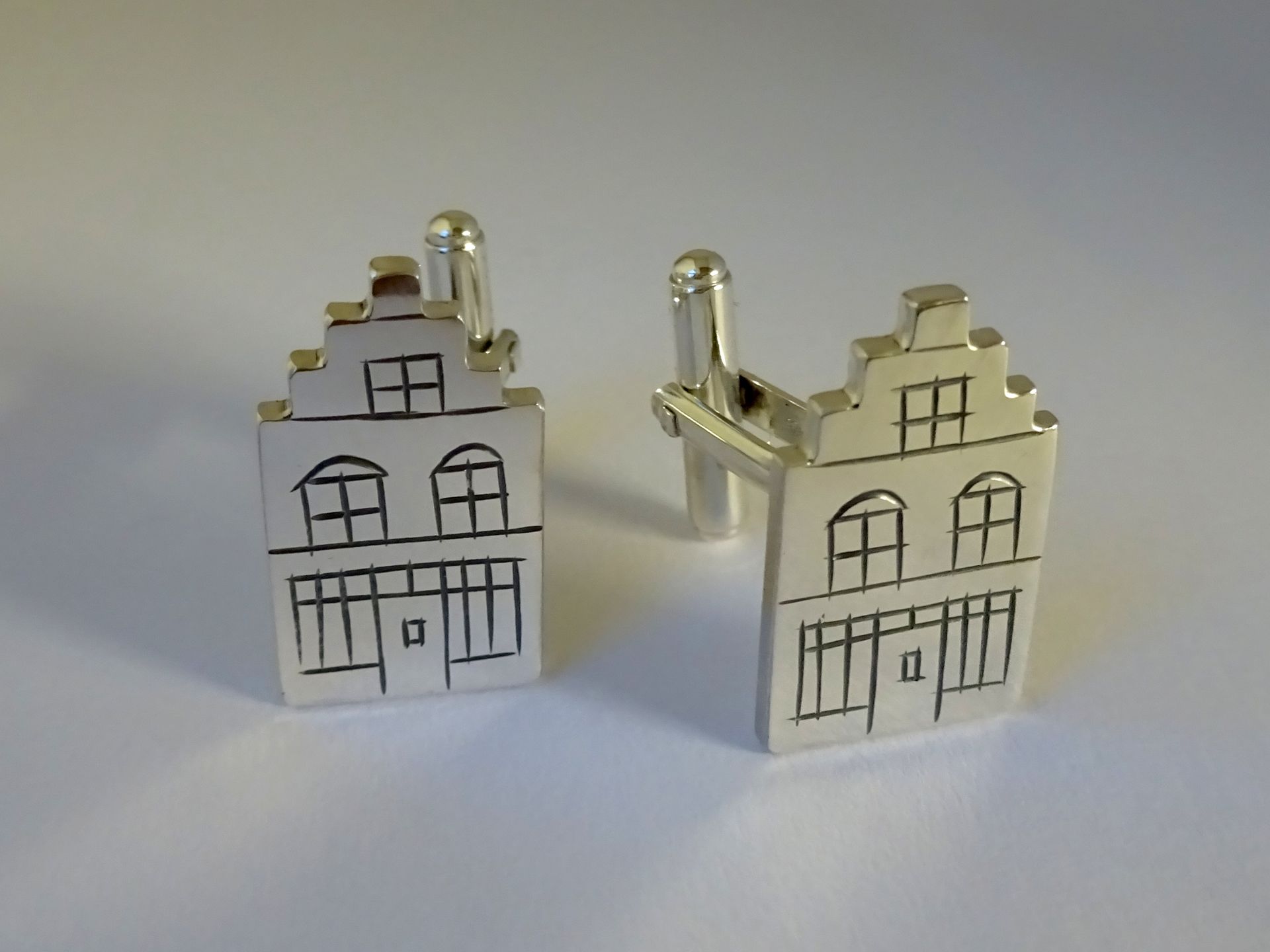 Unieke zilveren manchetknopen op maat gemaakt van een trapgevel huis.