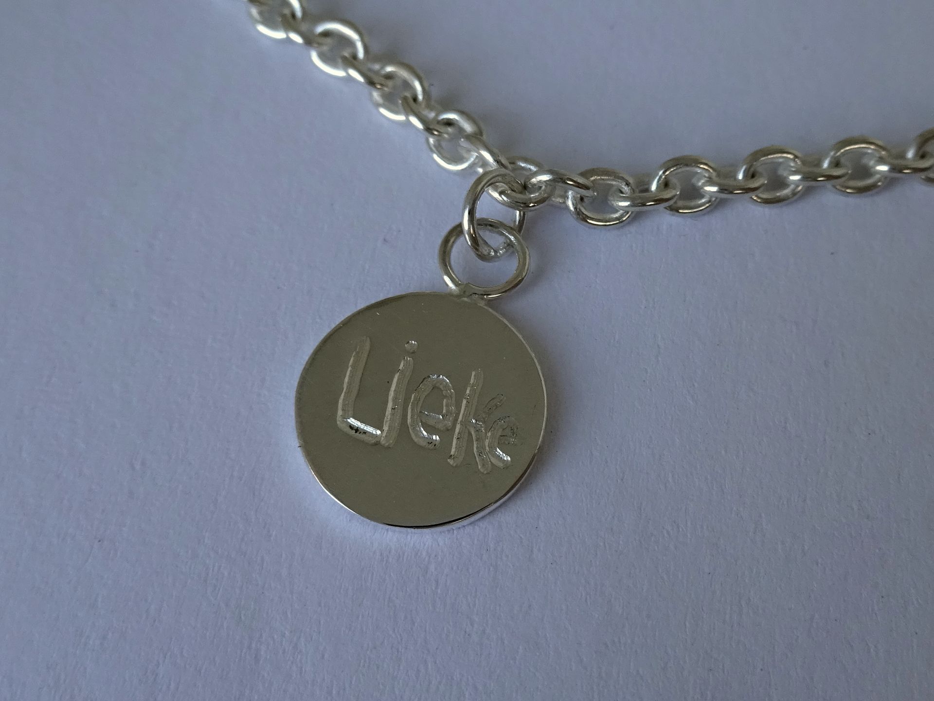 Handgeschreven tekst in een zilveren bedeltje.