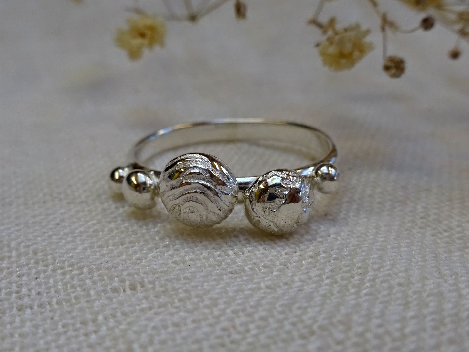 Rouwsieraad. Een herinnerring van zilver met vingerafdruk en bolletje met wereldkaart.