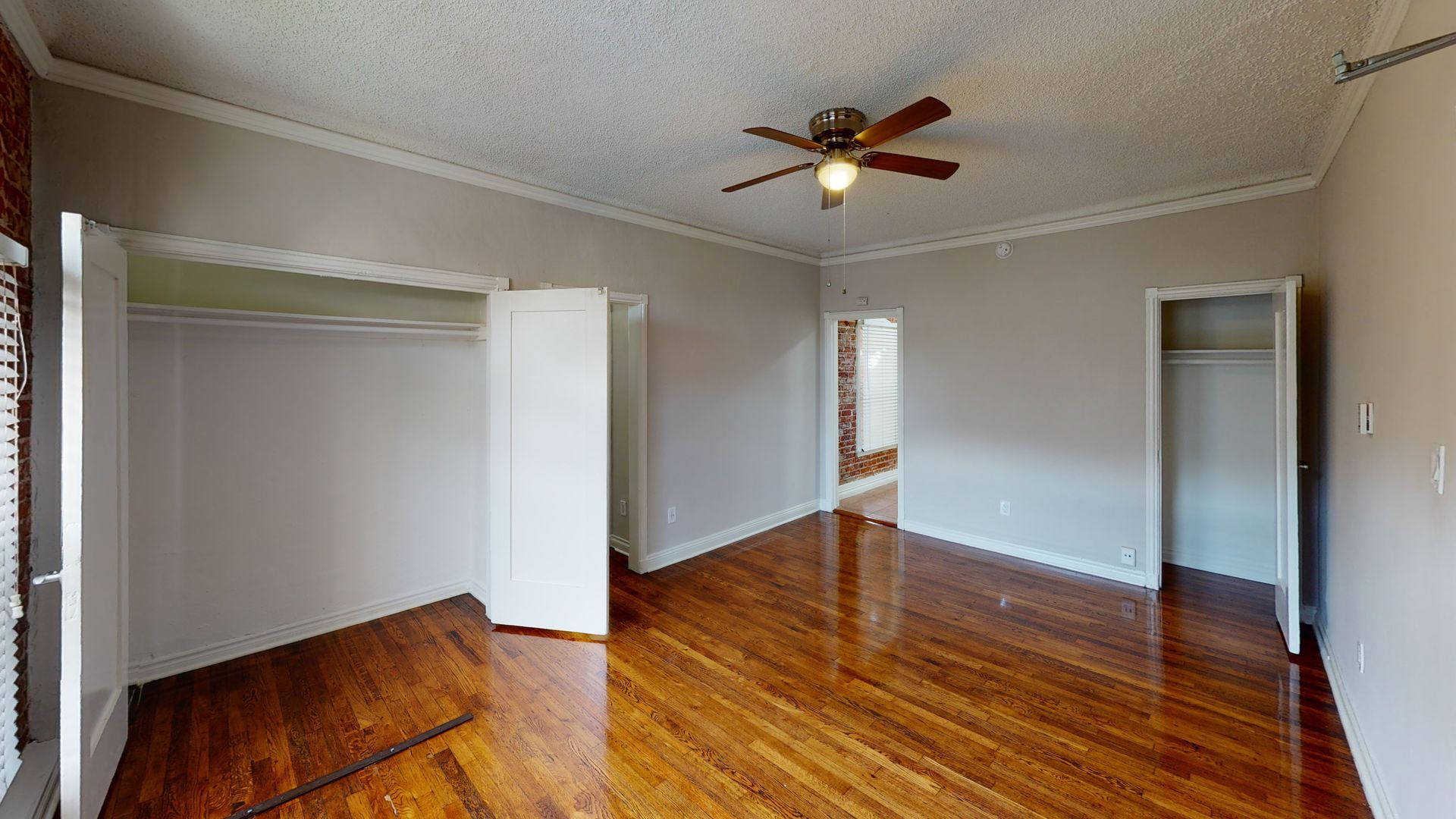 Empty room with hardwood floors, closets, and a ceiling fan.
