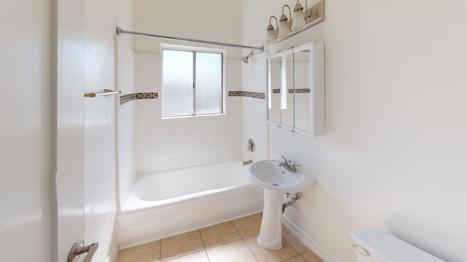 Bathroom with white tub, pedestal sink, mirrored medicine cabinet, and window.