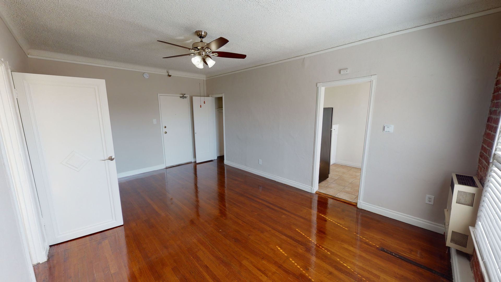 Empty room with hardwood floors, white doors, and a ceiling fan.