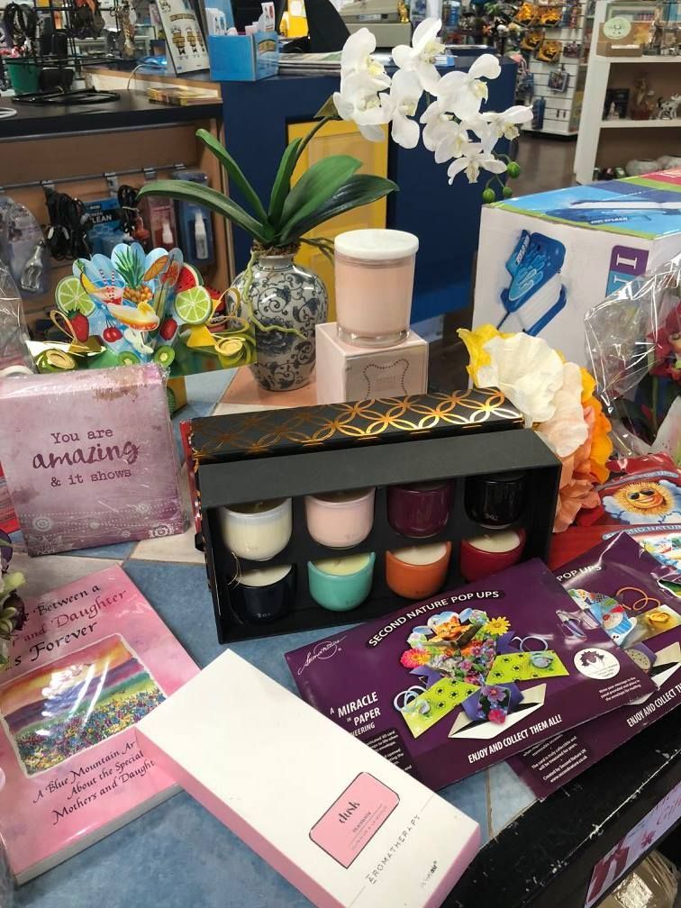 Display of gifts: candles, flowers, books, and decorative items on a table in a store setting — Enterprise Electrics NT Pty Ltd in Tennant Creek, NT