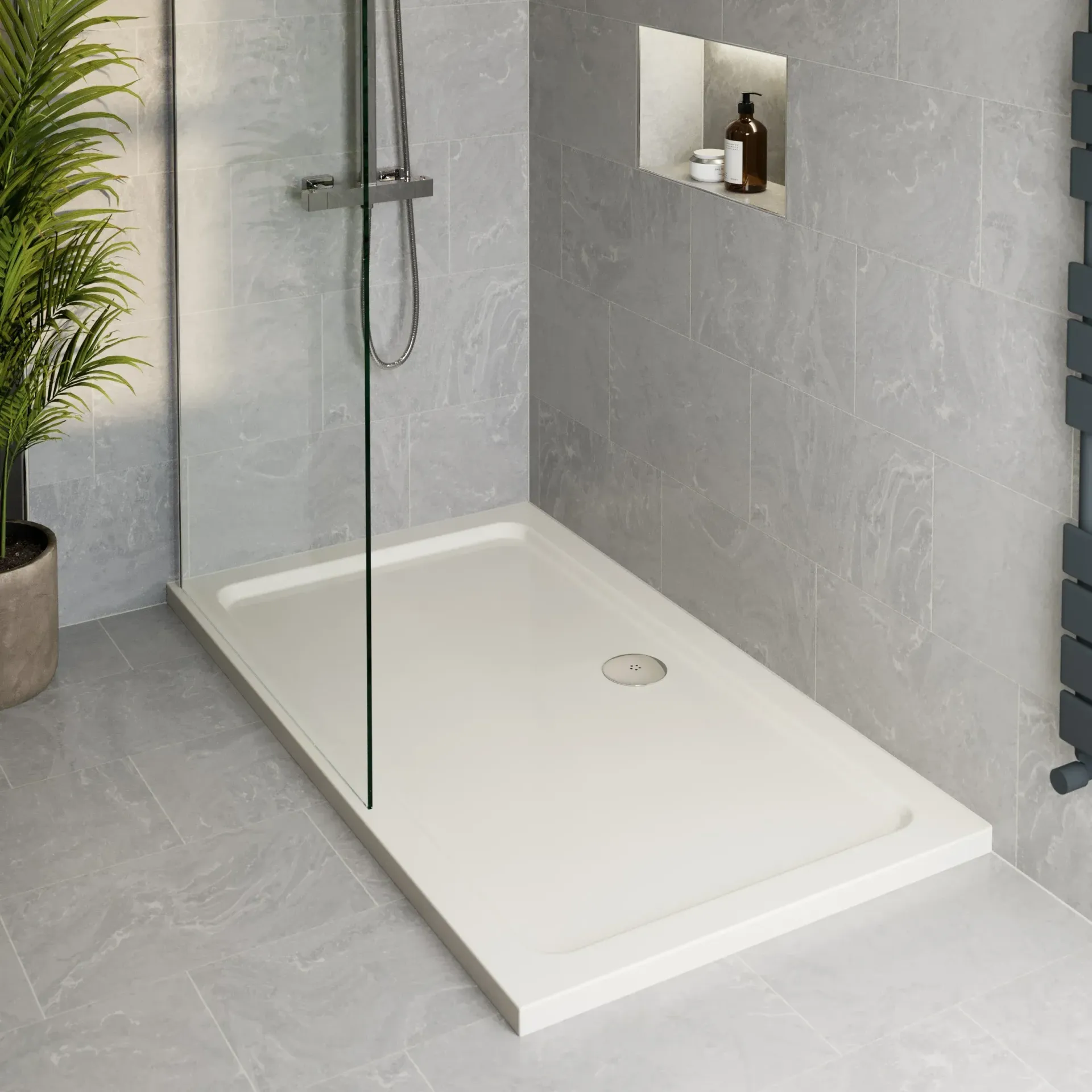 A white shower tray is in a bathroom next to a plant.