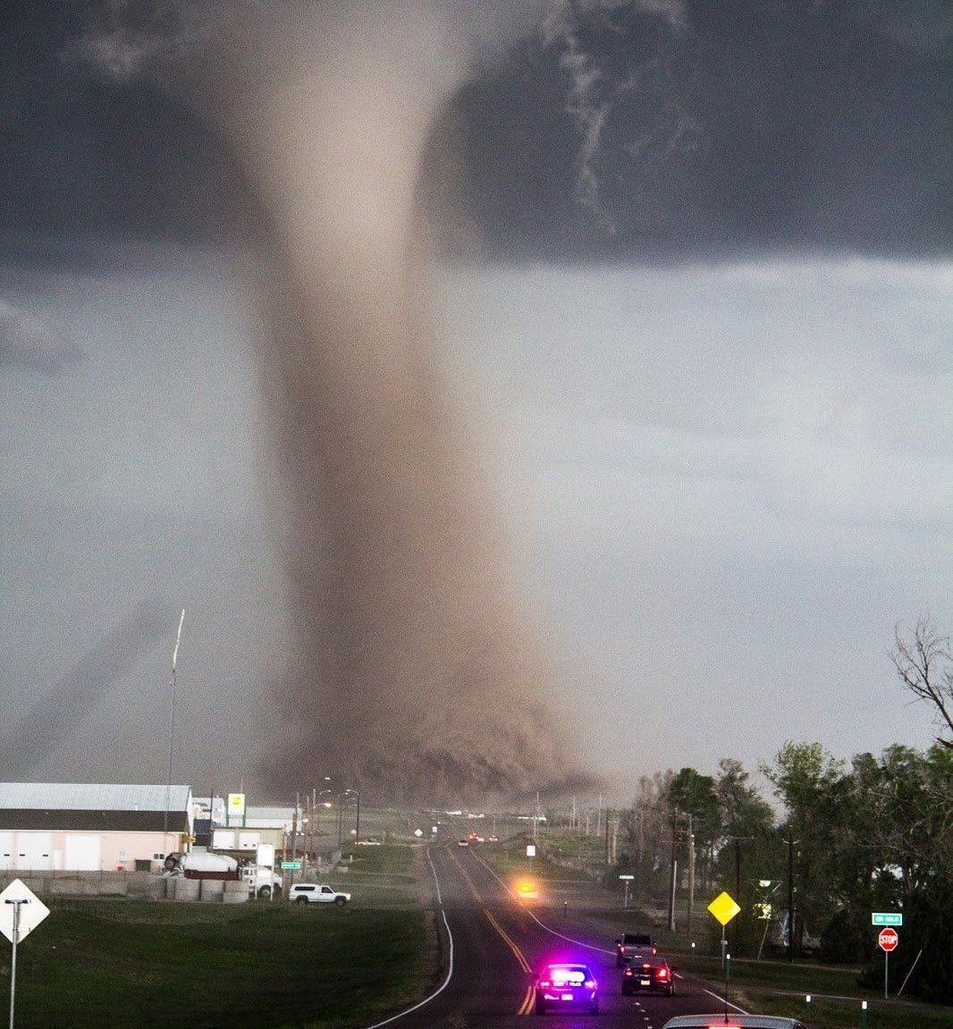 A tornado is coming down a road in a small town