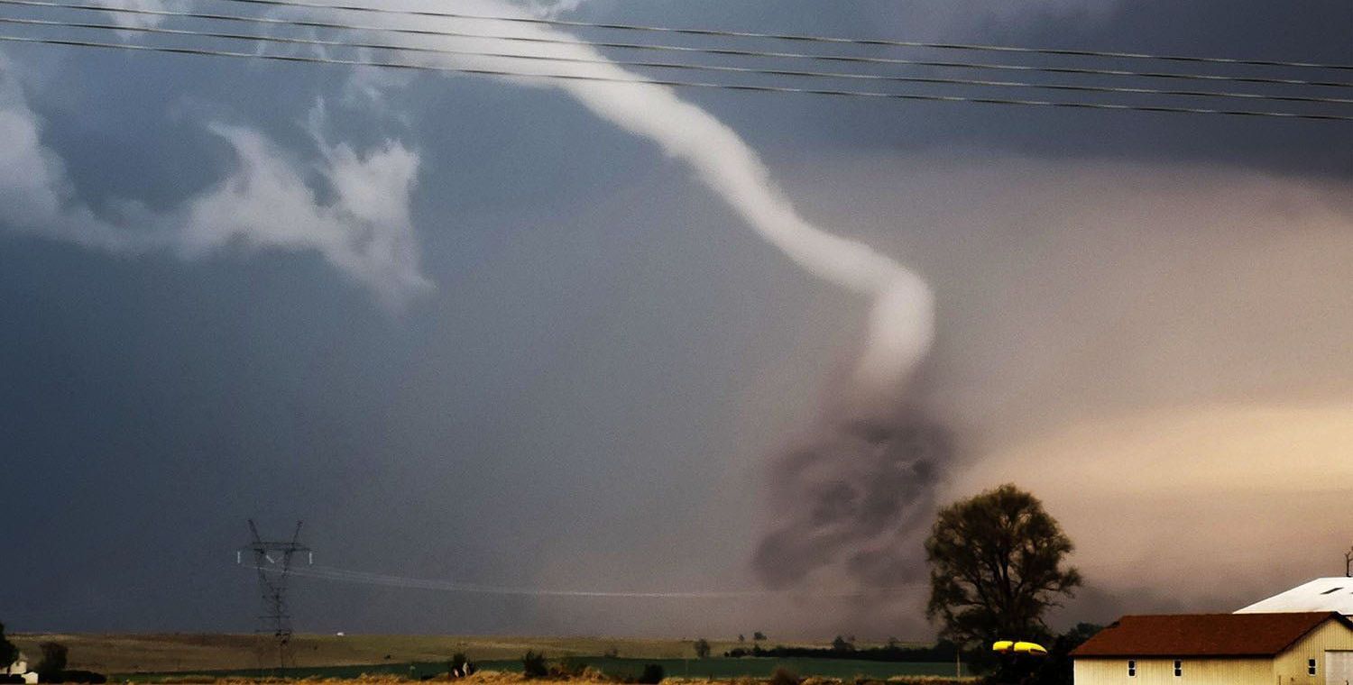 A tornado is moving through the sky over a house