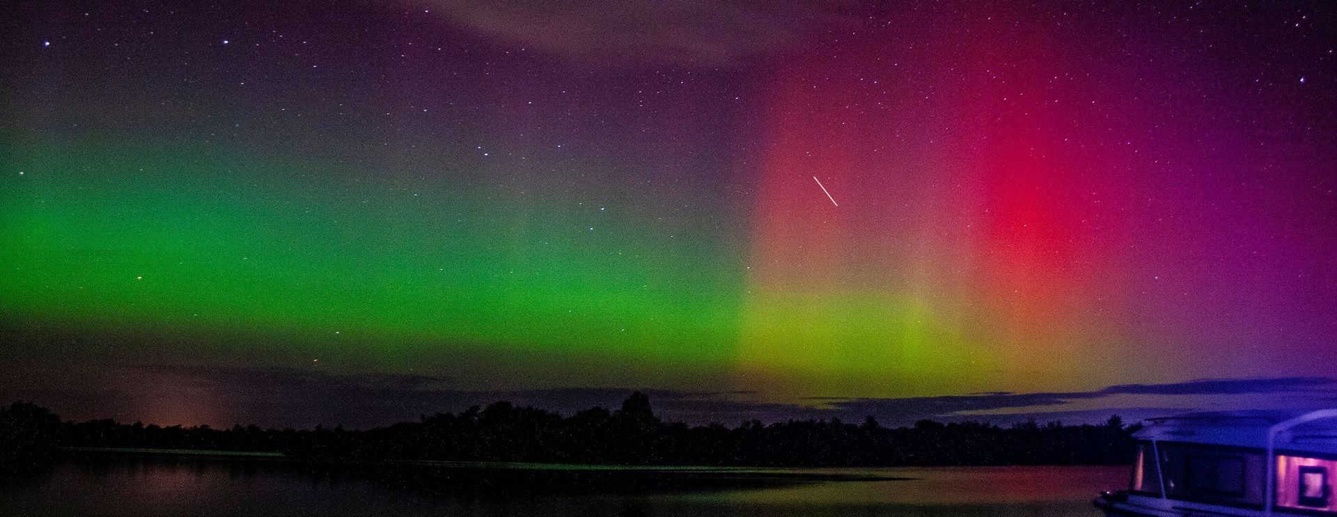 The aurora borealis is glowing in the night sky over a lake.