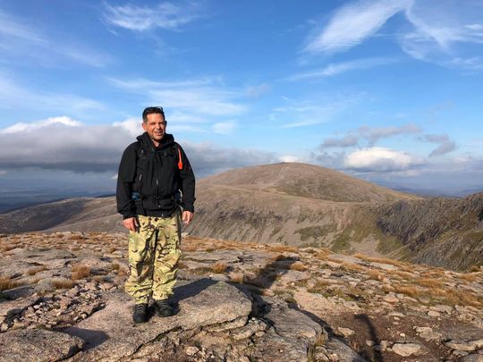 A man is standing on top of a rocky mountain.