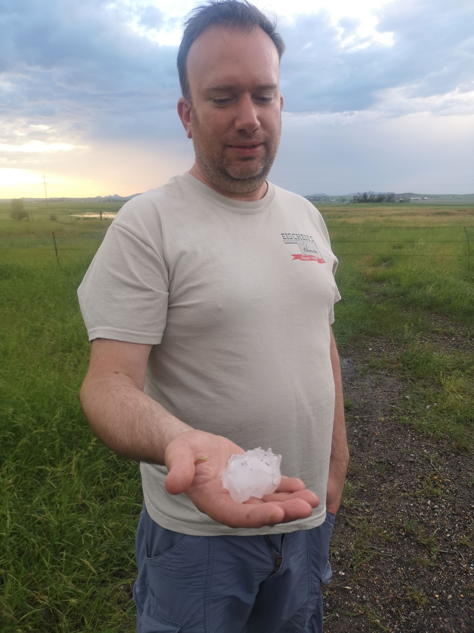 A man in a white shirt is holding a piece of hail in his hand