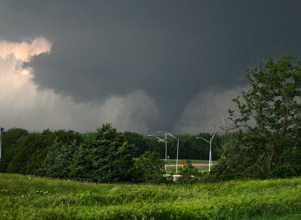 A tornado is moving through a field of grass and trees.