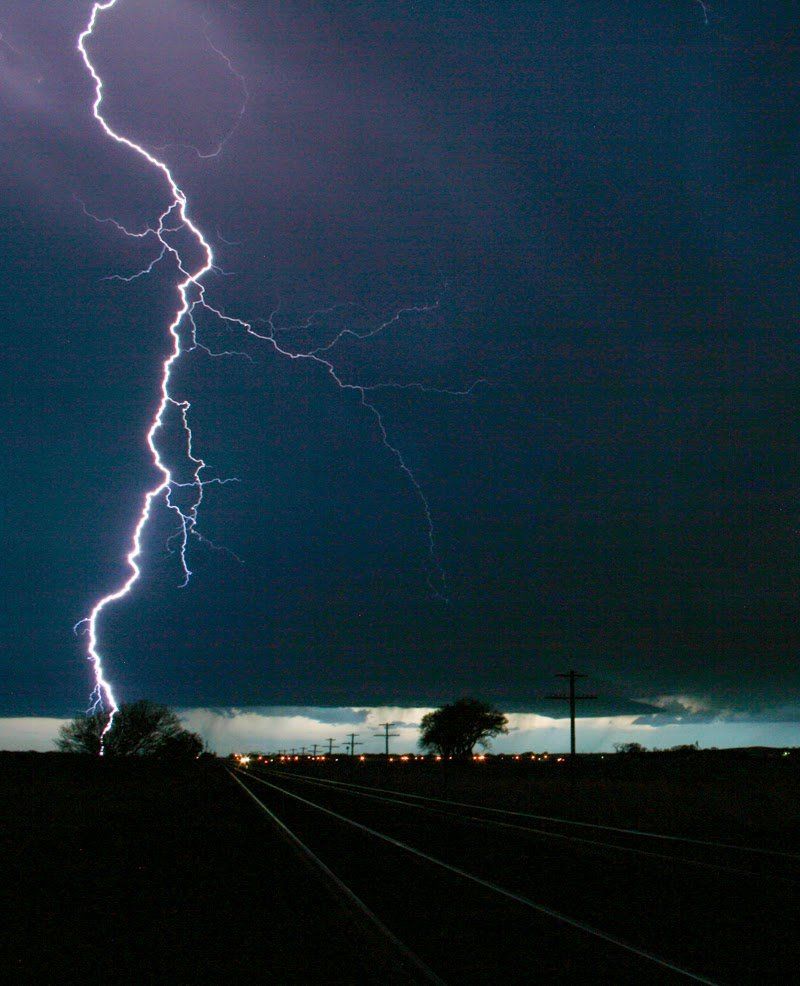 A lightning bolt strikes over a train track at night