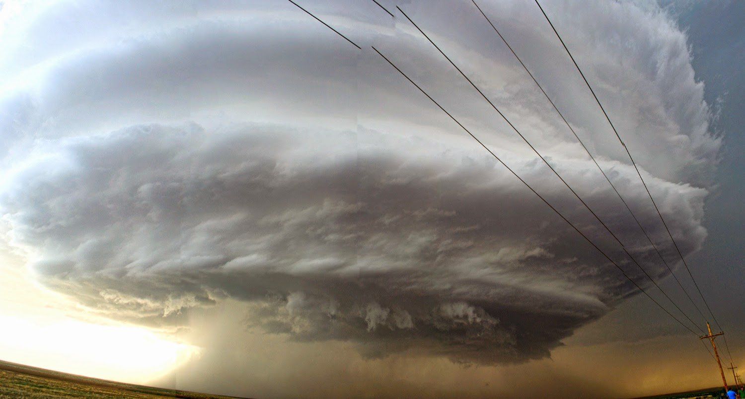 A large cloud in the sky with power lines in the foreground
