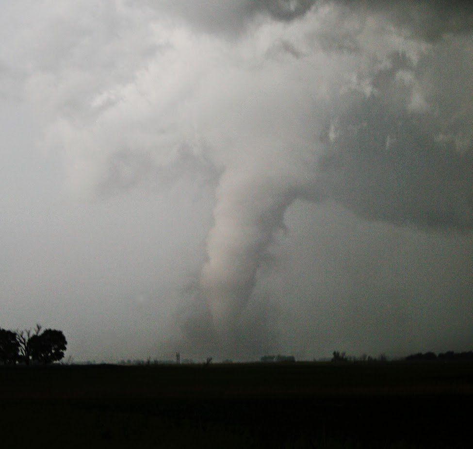 A tornado is moving through the sky over a field.