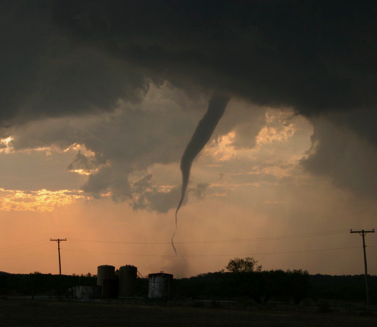 A tornado is moving through a field at sunset