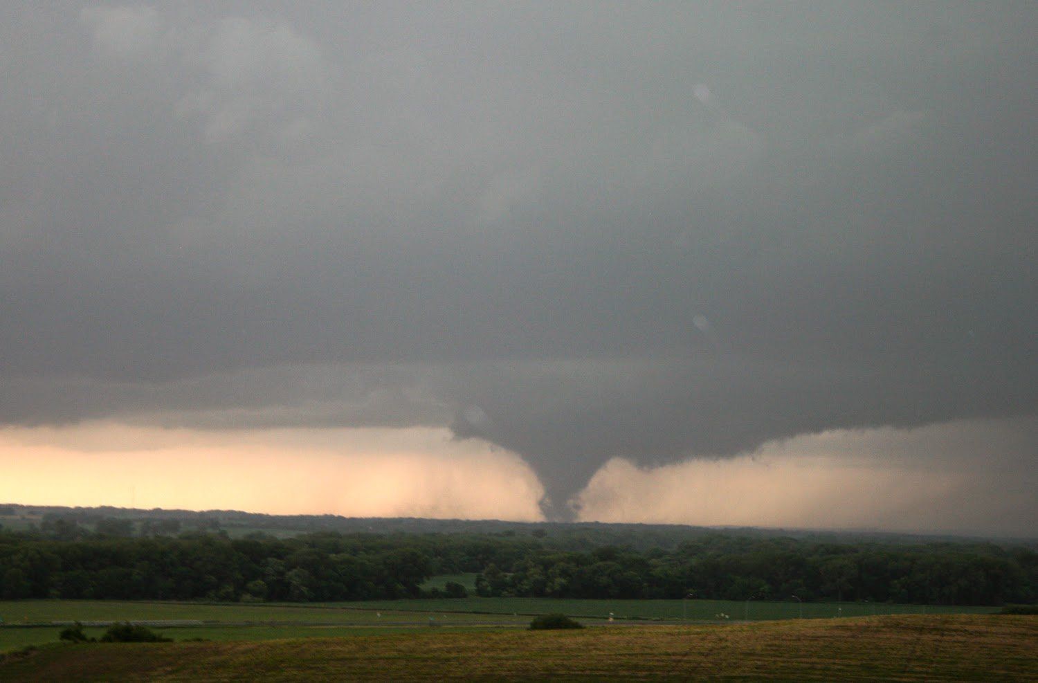 A tornado is moving through the sky over a field.