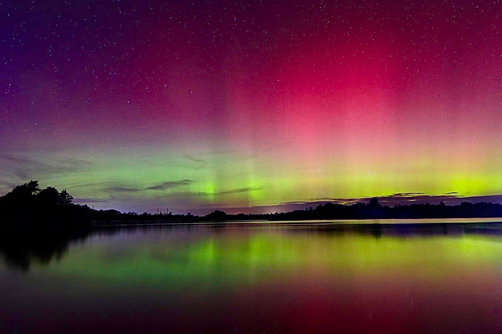 The aurora borealis is reflected in the water of a lake.
