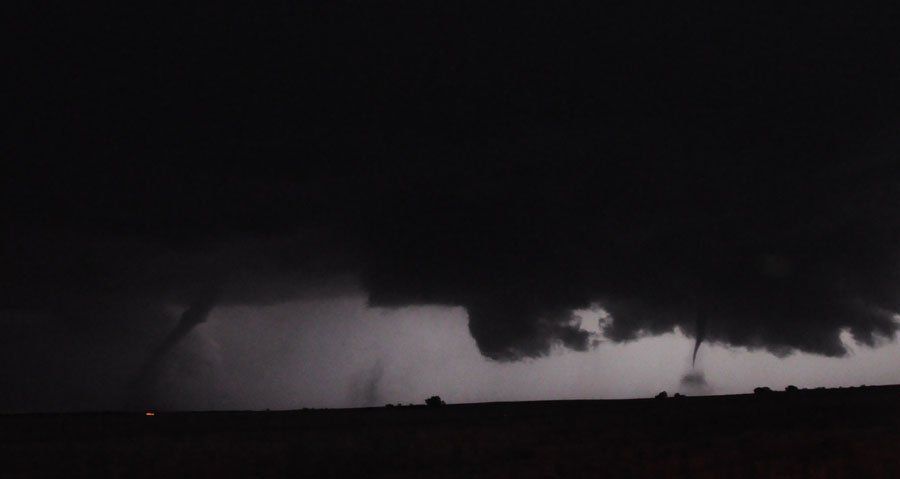 A tornado is moving through a dark sky at night.