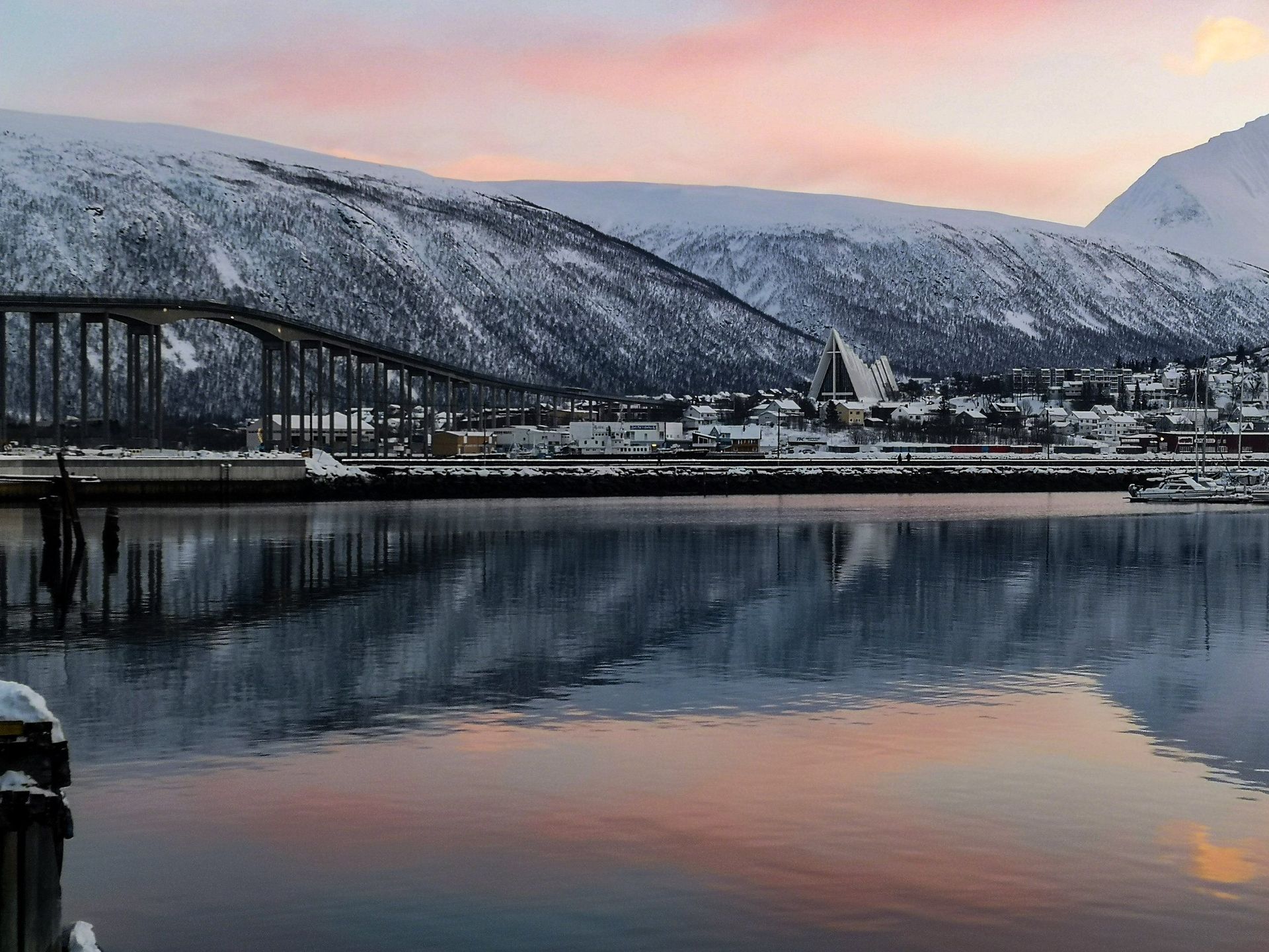 A bridge over a body of water with mountains in the background.