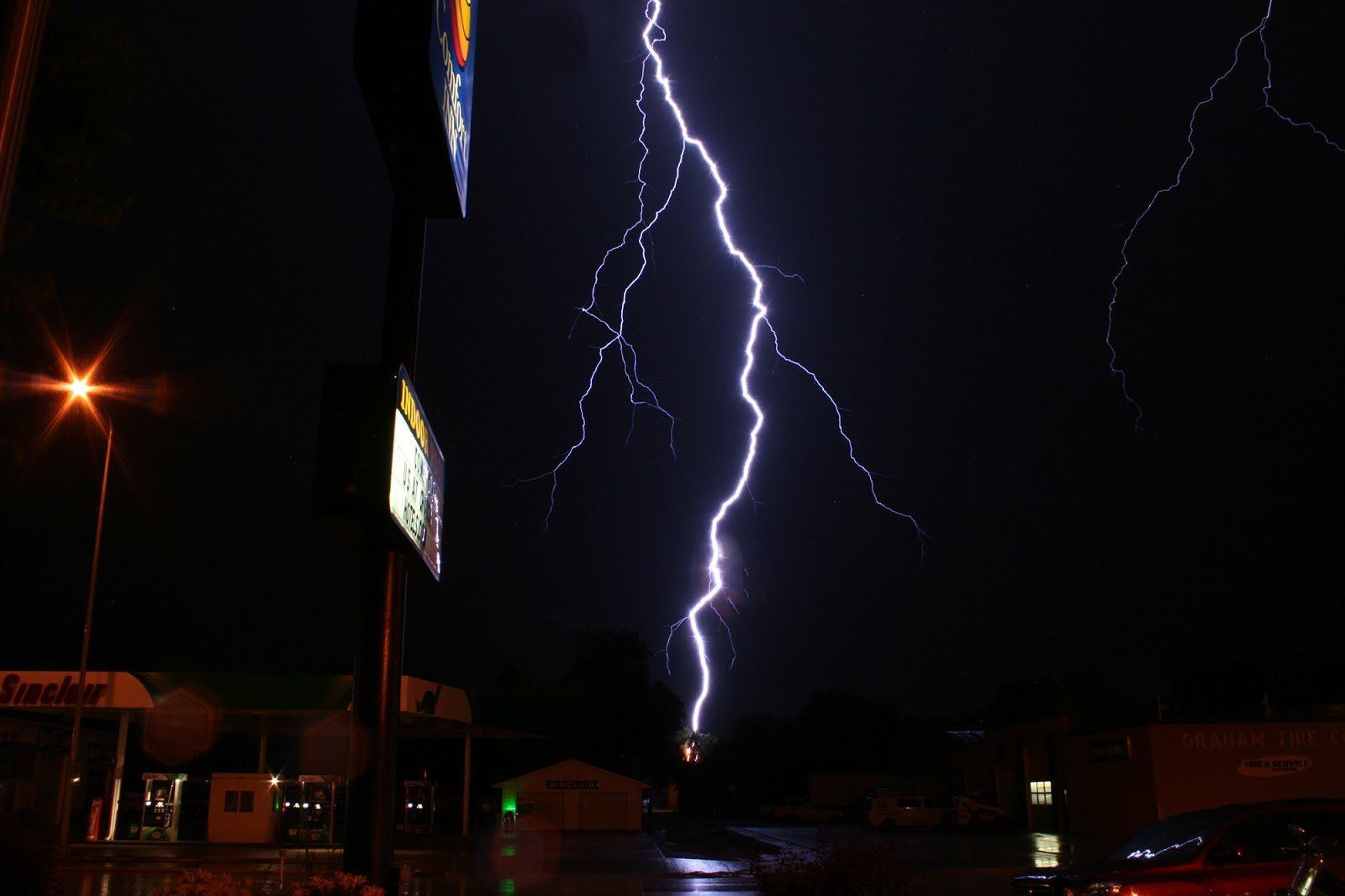 A lightning bolt is striking a building at night.