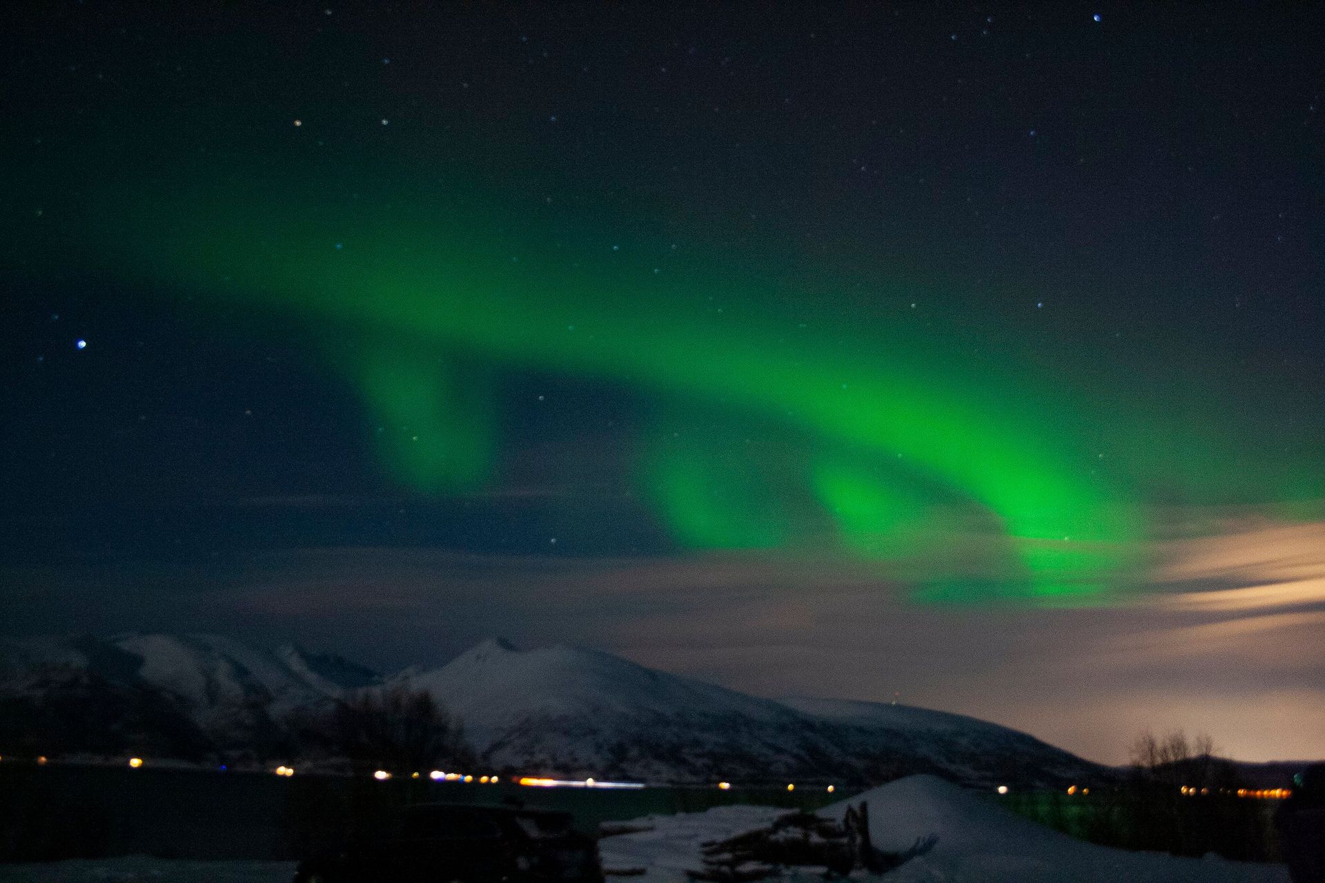 The aurora borealis is dancing in the night sky over a snowy landscape.