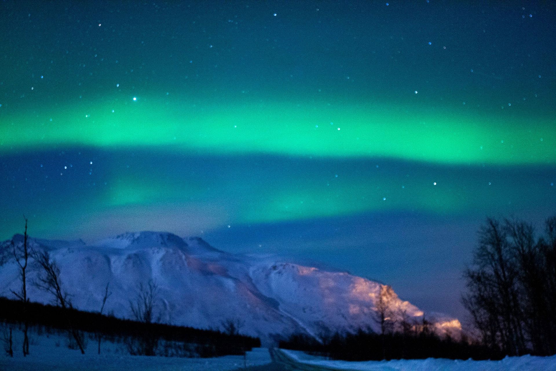 The aurora borealis is shining over the mountains at night.