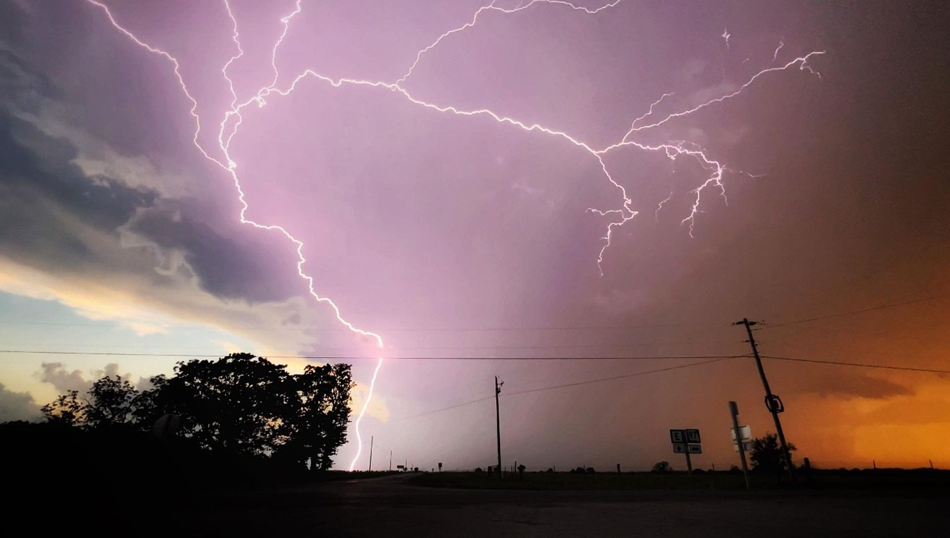 Lightning strikes in the sky over a field at sunset