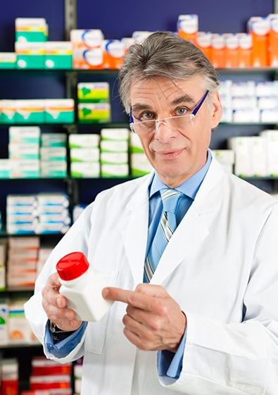A pharmacist is pointing at a bottle of pills in a pharmacy.
