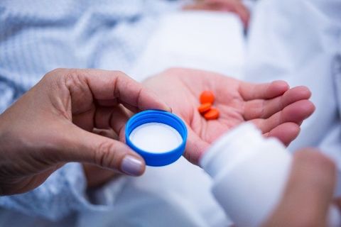 A person is holding a bottle of milk and pills in their hand.