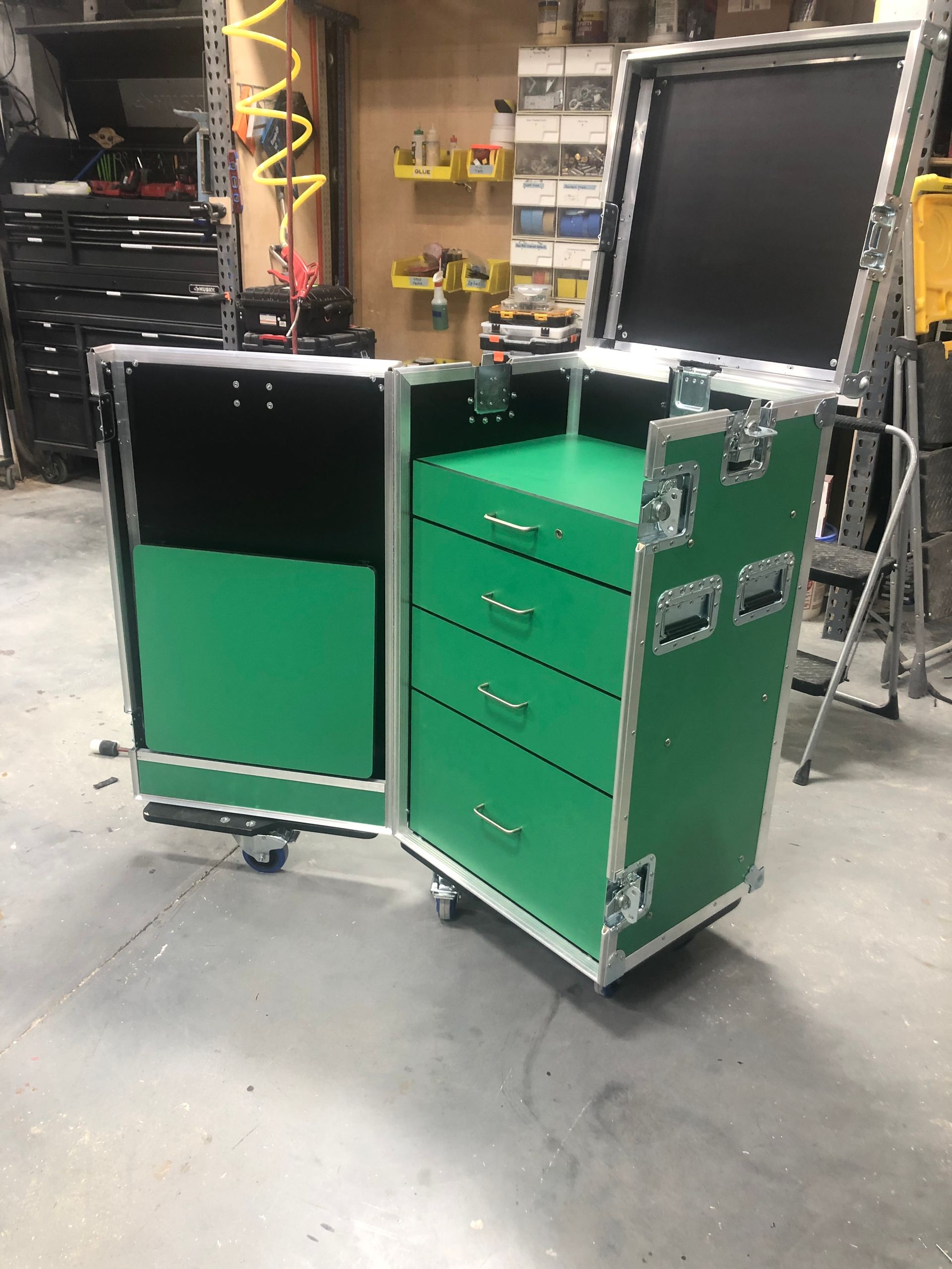 Green storage cabinet with drawers and screen, open in a workshop.
