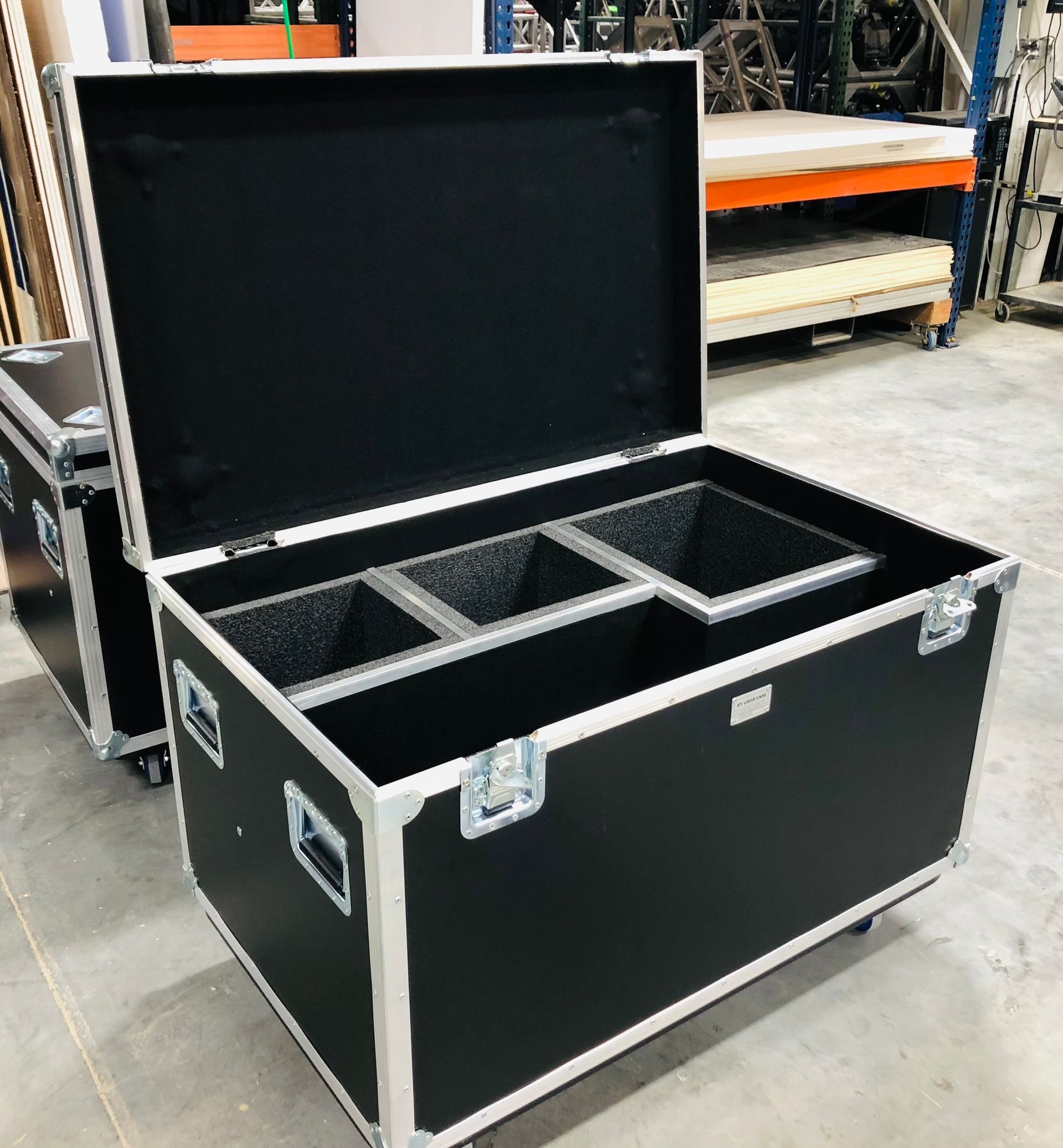 Black equipment case with open lid, divided compartments, metal accents.