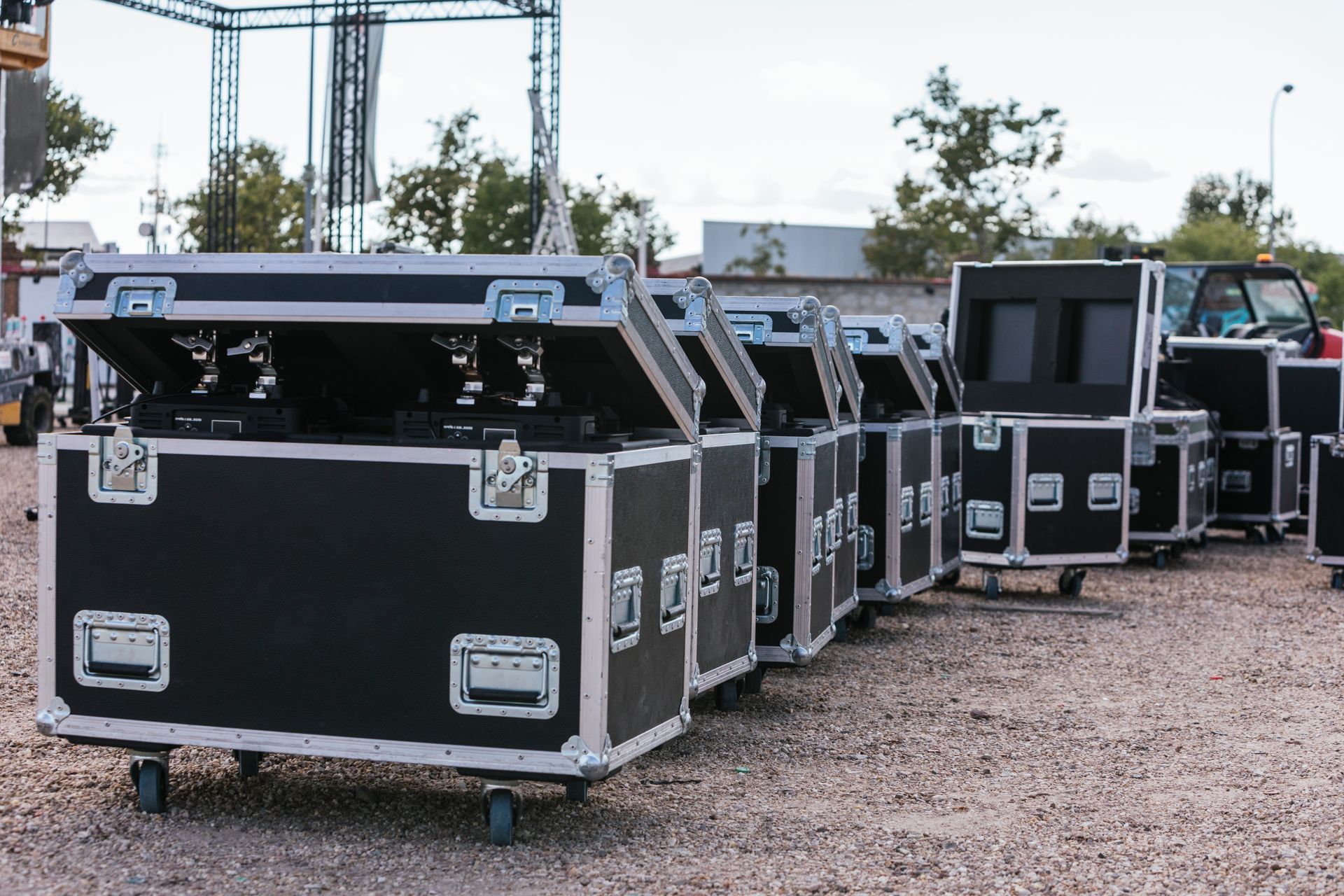 Black road cases with silver trim, lined up outside. Some have open lids, revealing equipment.