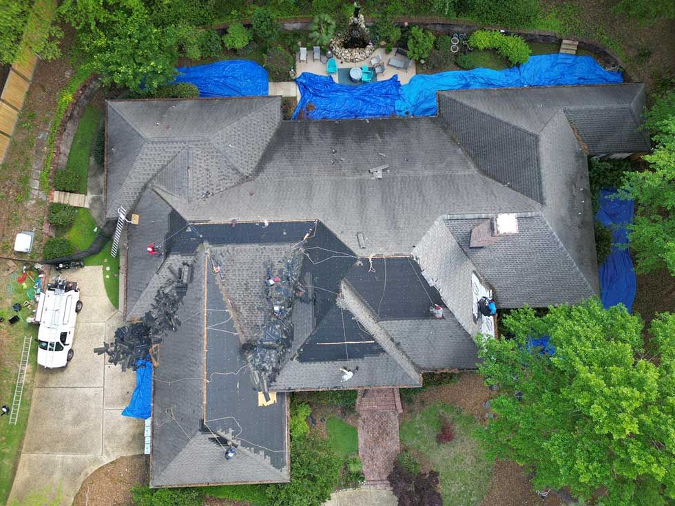 An aerial view of a large house with a roof that is being repaired.