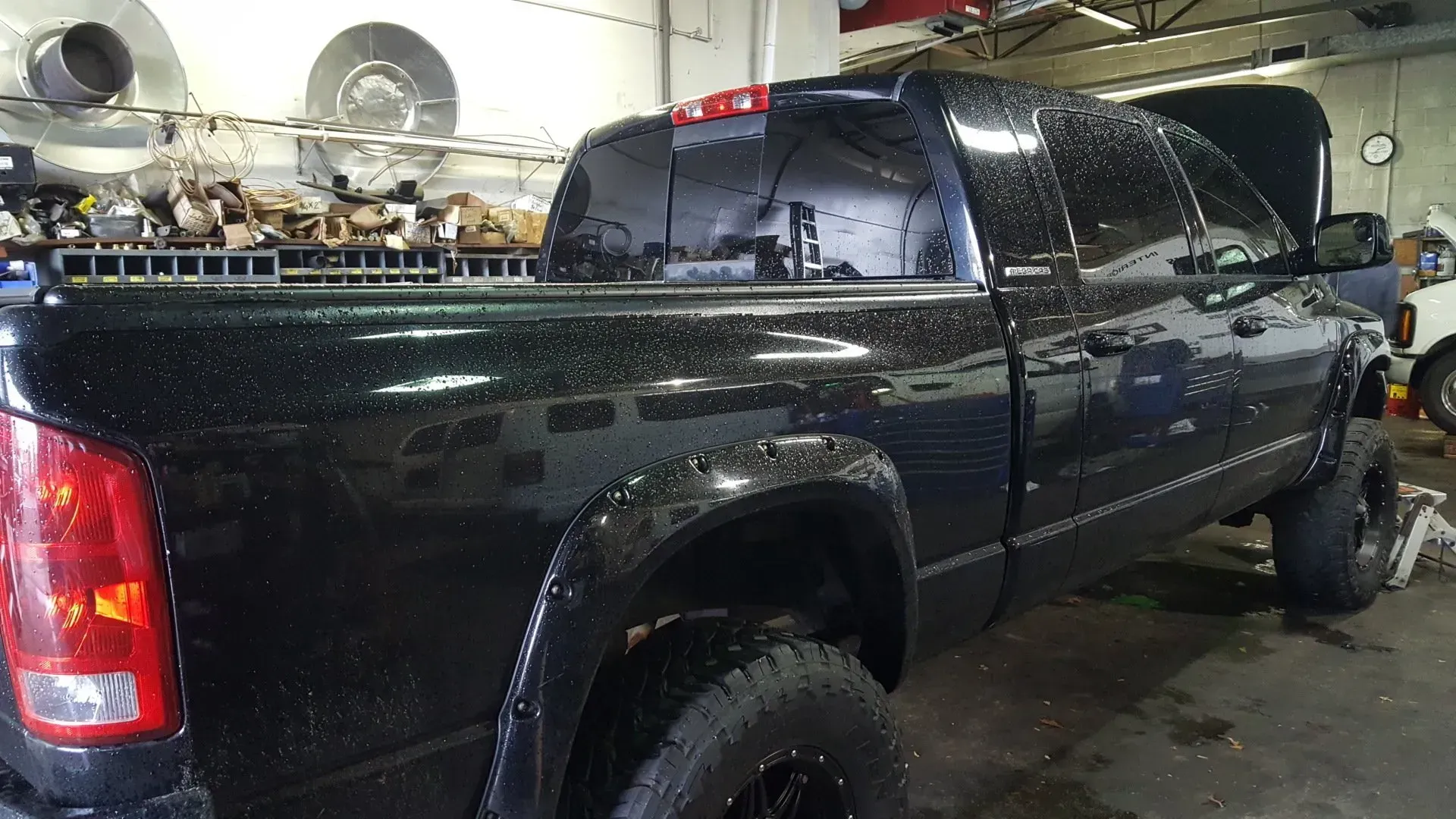 A black truck is parked in a garage with the hood up.