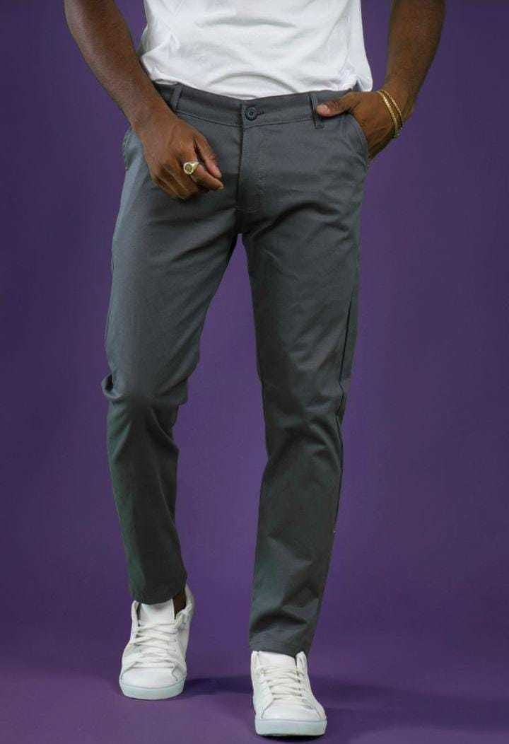 Hombre con pantalón y zapatillas negras, camisa blanca, fondo morado.