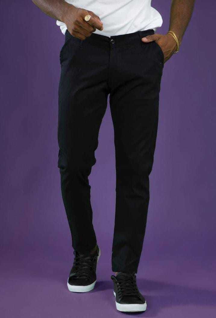 Hombre con pantalón y zapatillas negras, camisa blanca, fondo morado.