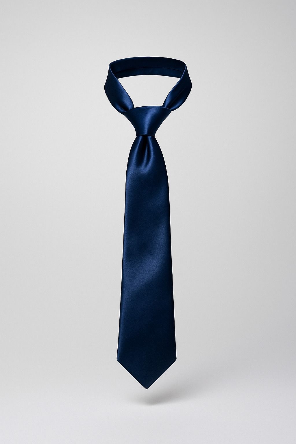 Corbata azul marino con nudo sobre fondo gris claro.