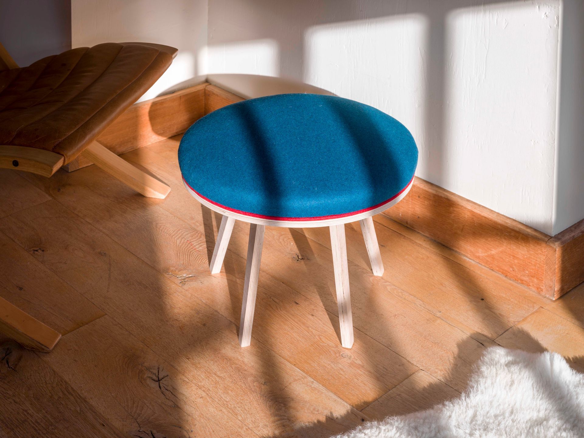 Teal upholstered modern round birch ply footstool with piping