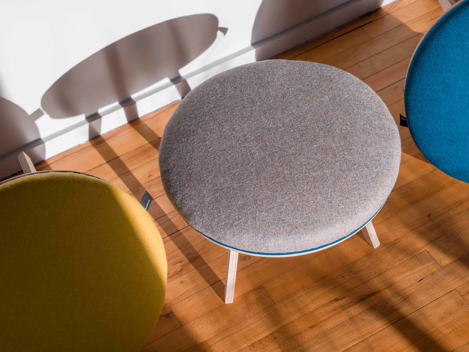 Grey wool upholstered modern round birch ply footstool