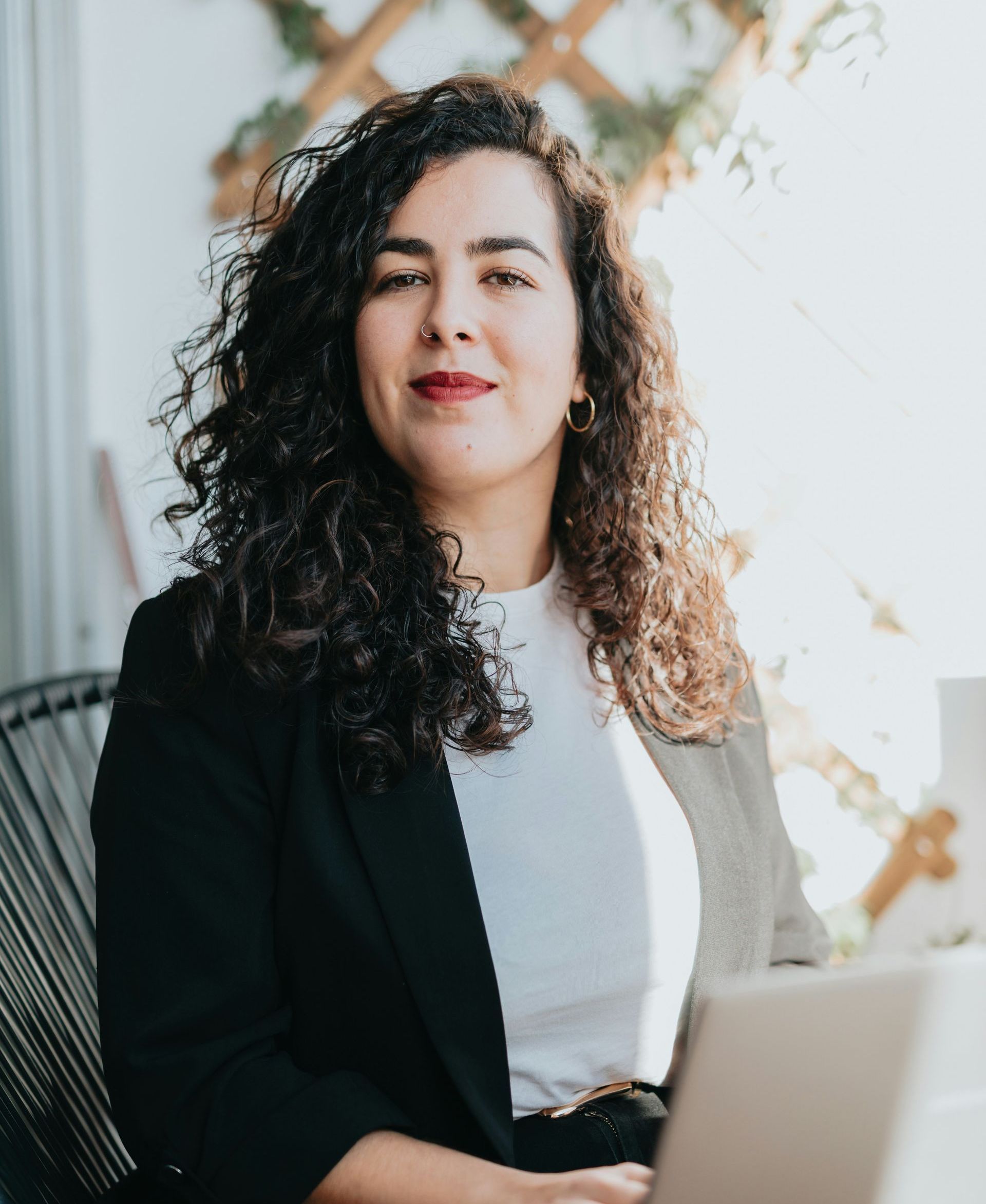 A woman with curly hair is sitting in front of a laptop computer.