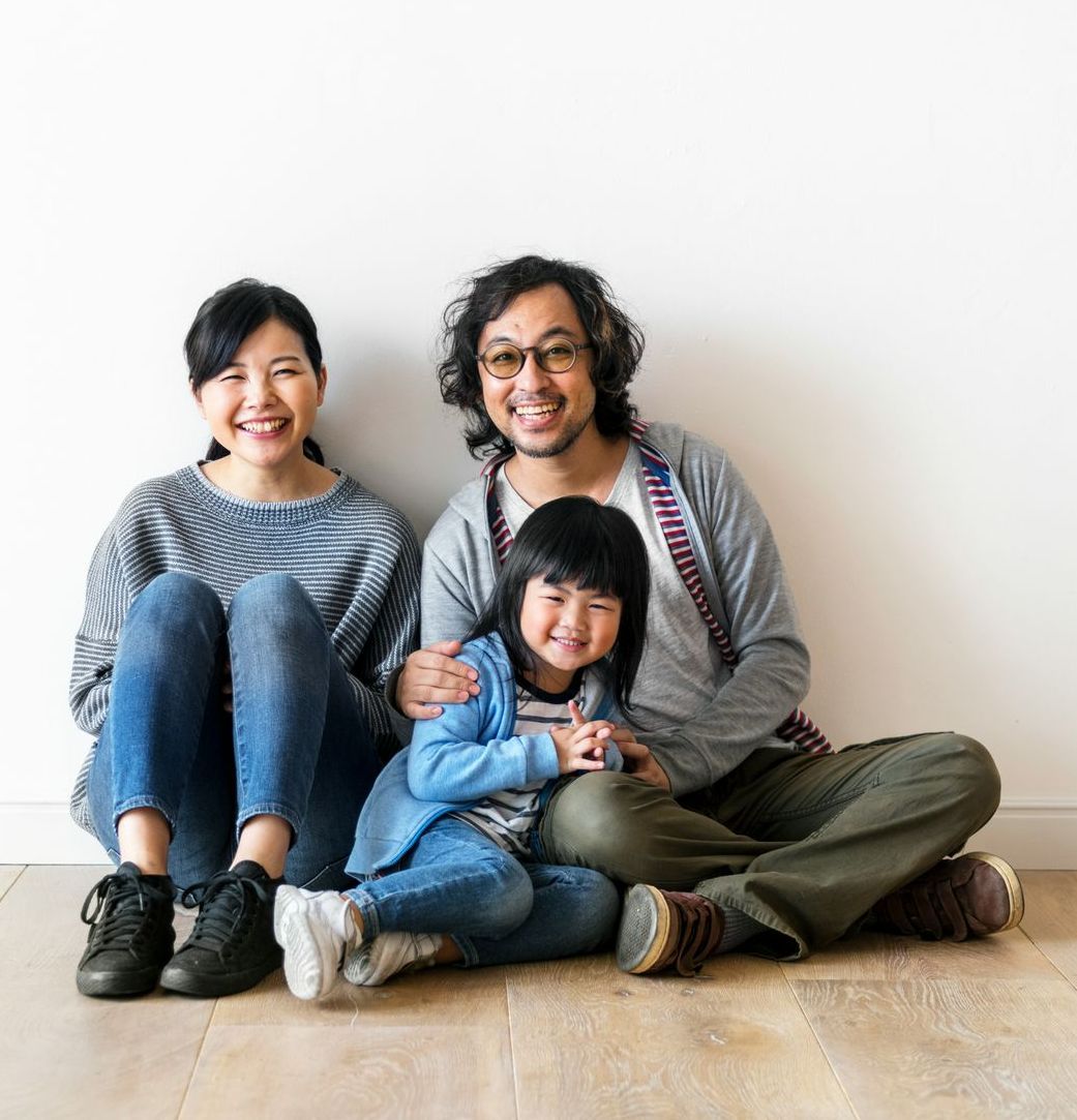 A family is sitting on the floor posing for a picture.