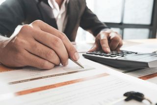 A man is using a calculator and writing on a piece of paper.