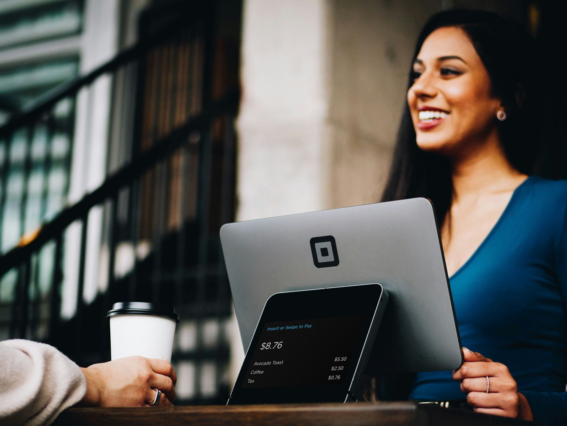 A woman is sitting at a table with a laptop and a cup of coffee.