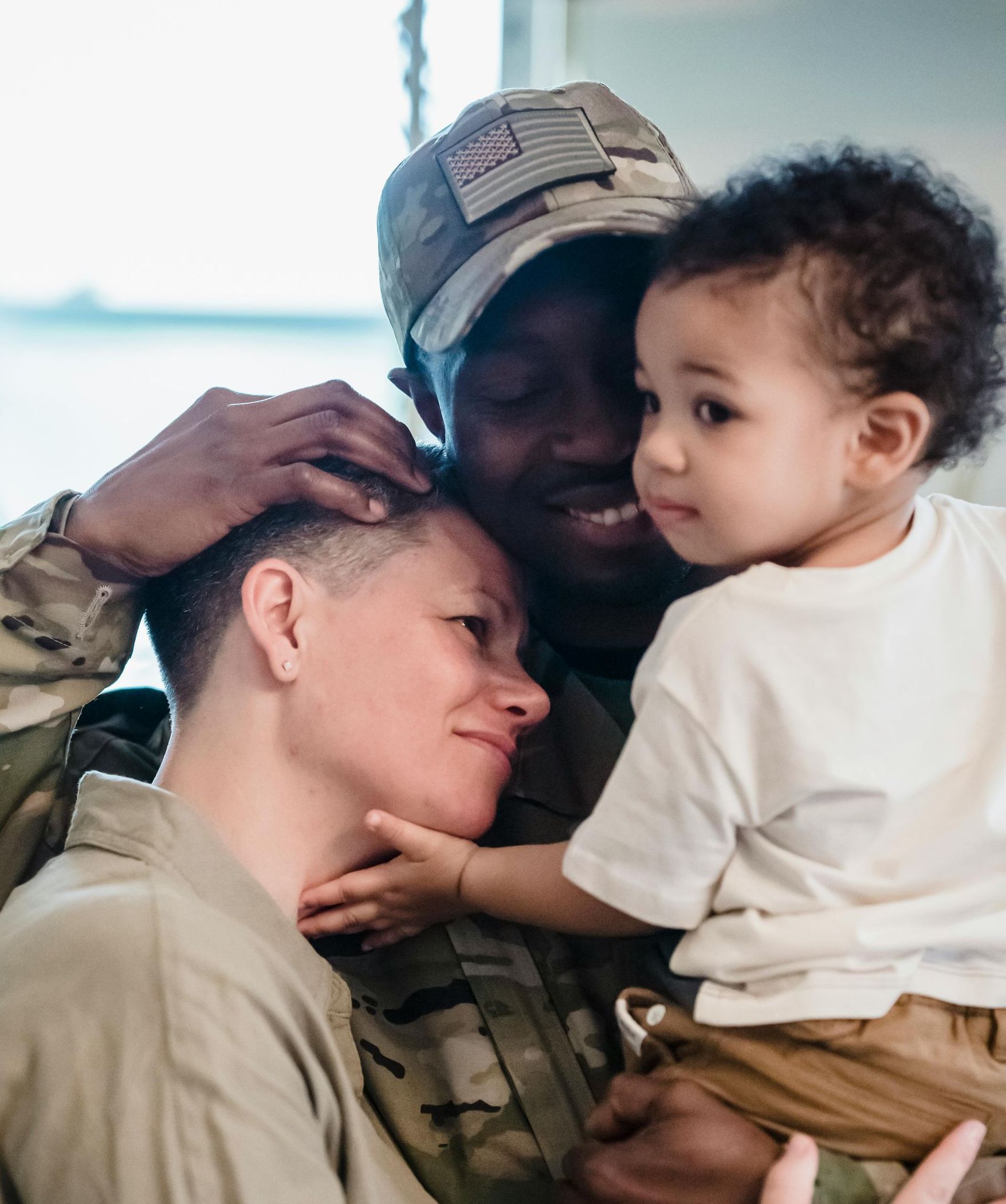 A man in a military uniform is holding a baby in his arms.