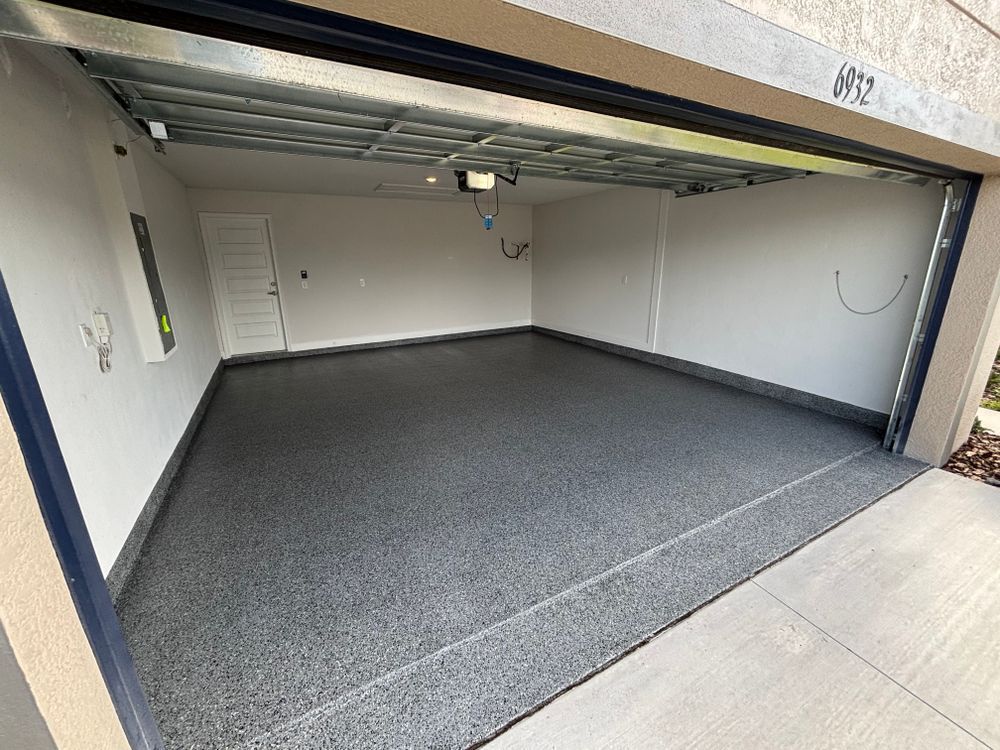 A garage with a garage door open and a gray floor.