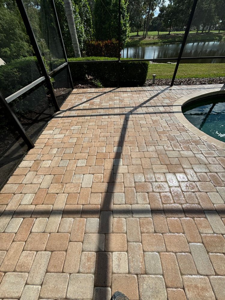 A person is standing on a brick patio next to a pool.