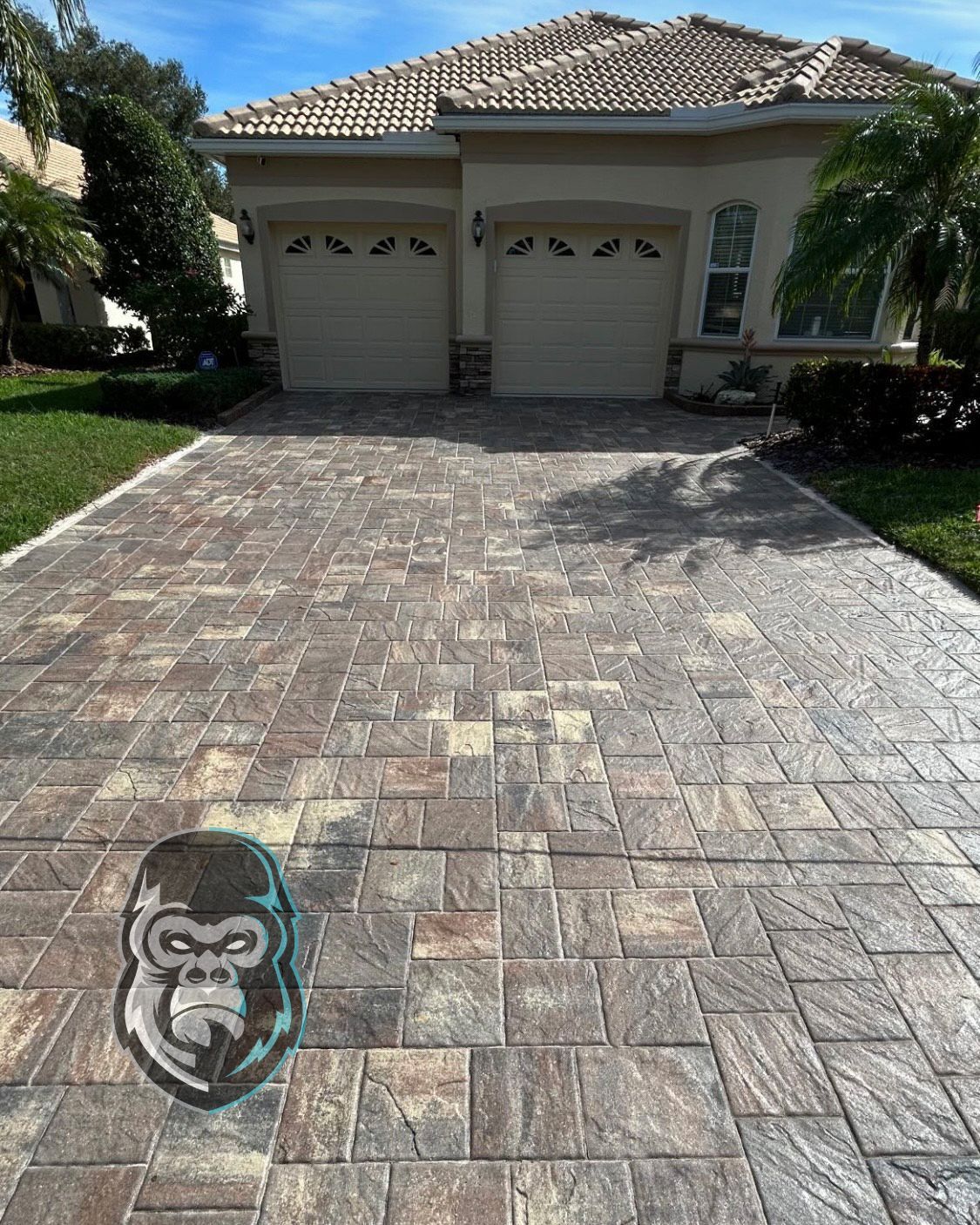 A brick driveway with a drawing of a gorilla on it in front of a house.